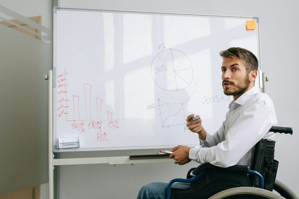 a man in a wheelchair writing on a whiteboard