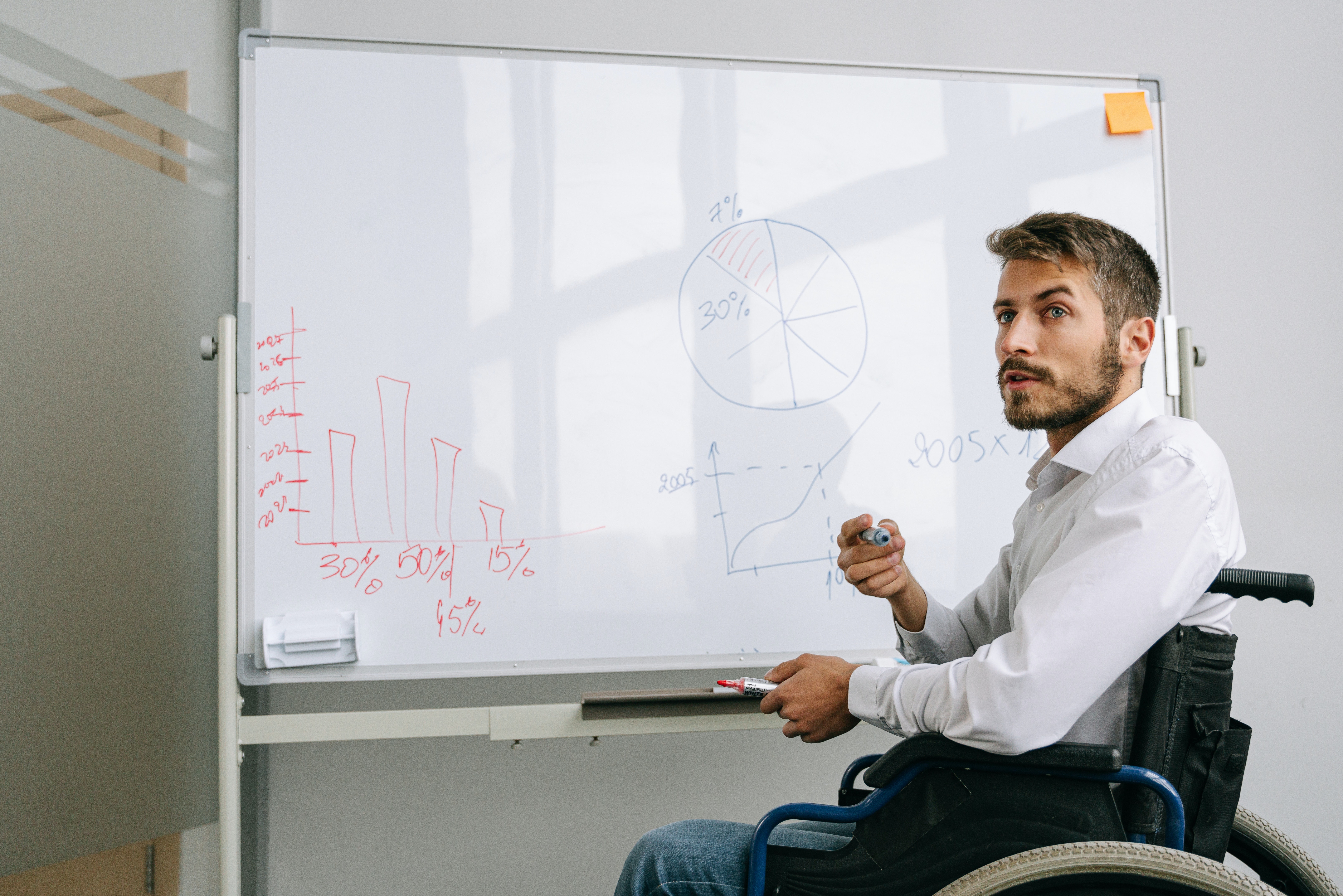 Aman in a wheelchair writing on a whiteboard