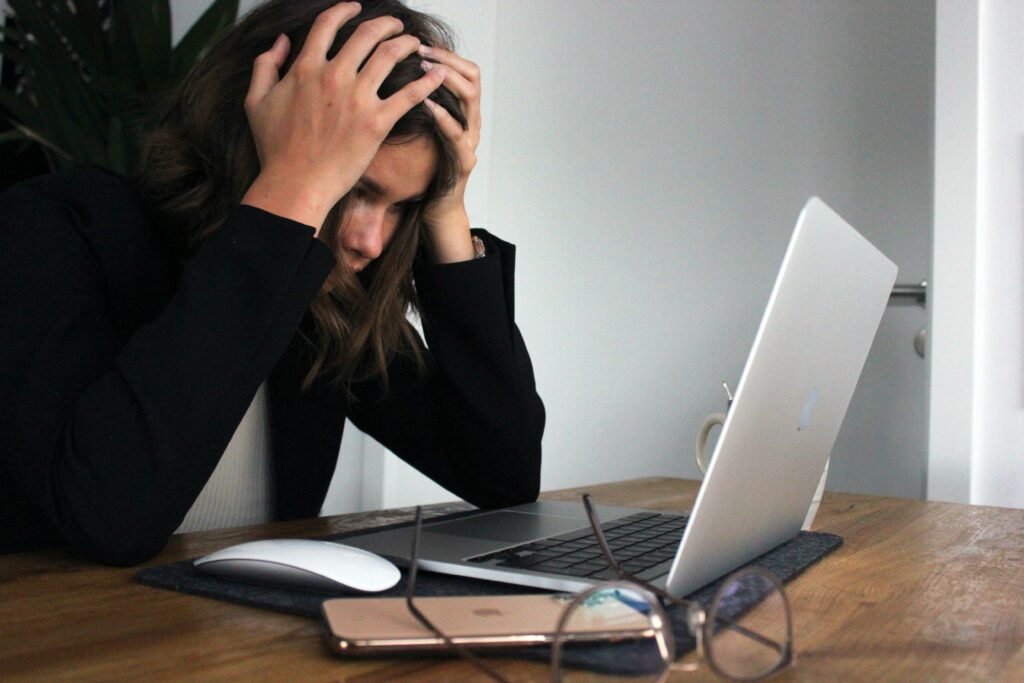 Woman with her head in her hands staring at a laptop screen