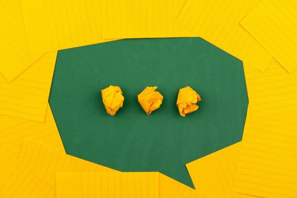 Three crumpled pieces of yellow paper as dots on a speech bubble